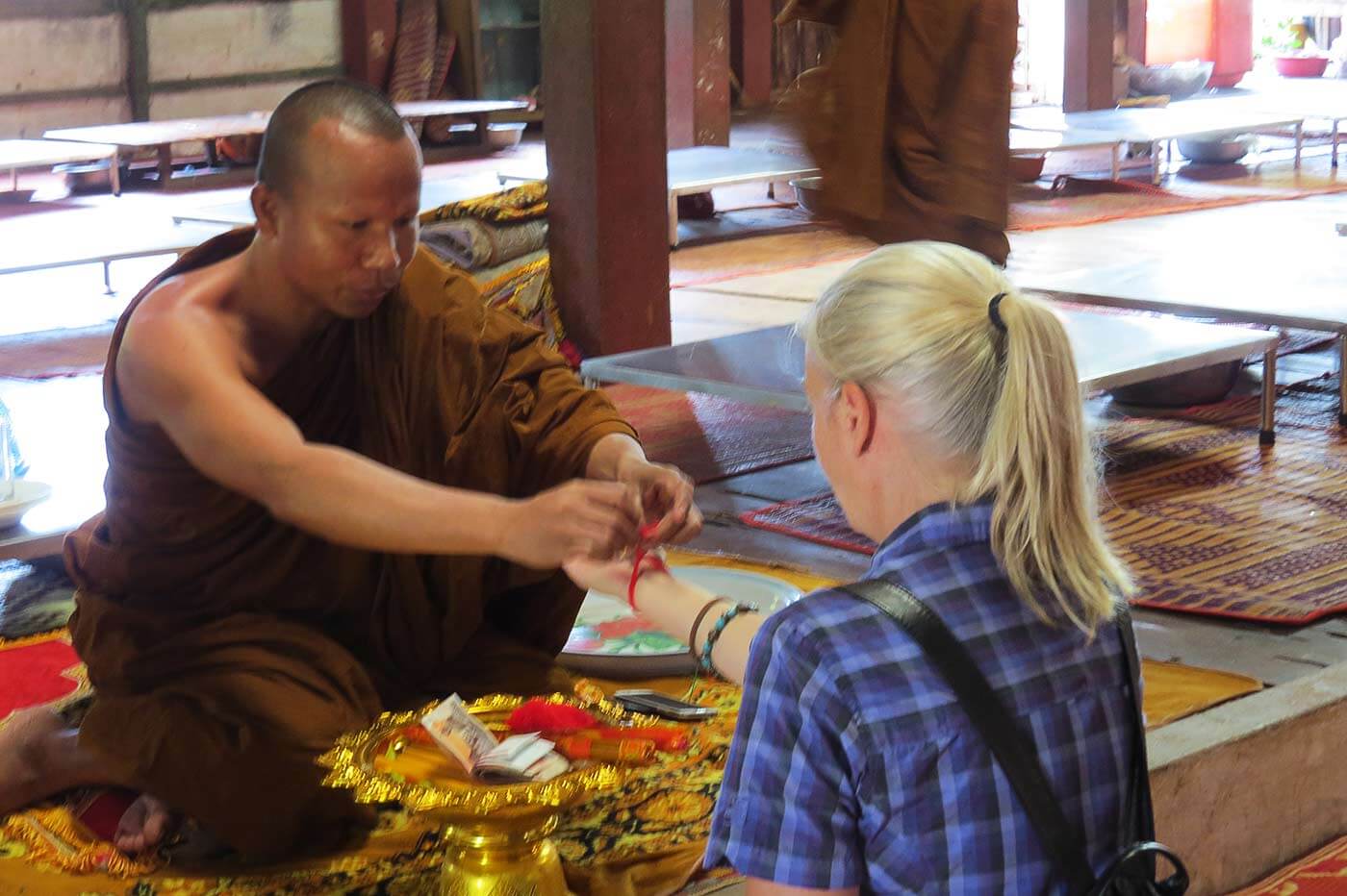 Der Mönch knotet ein rotes Glücksbändchen um mein Handgelenk - Kong Moch Pagode in Siem Reap