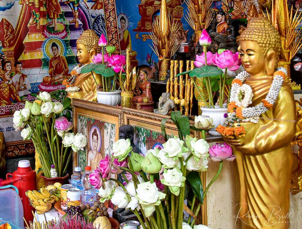 Mit vielen Lotosblumen geschmückte Buddhastatuen im Wat Steung Meanchey in Phnom Penh