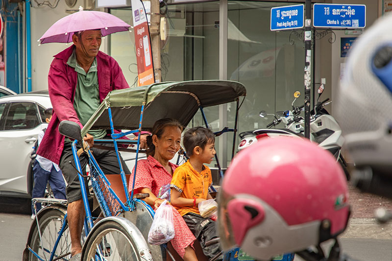 Rikscha Fahrer mit Fahrgästen im Zentrum der Hauptstadt Phnom Penh