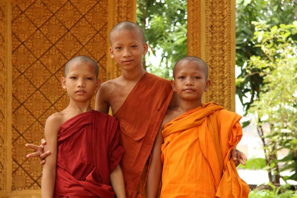 Three young monks wearing robes with different orange colour. 