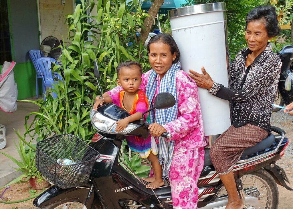 Happy Khmer family on a motorbike with a new Water Filter by charity "Wasserzeichen" from Germany