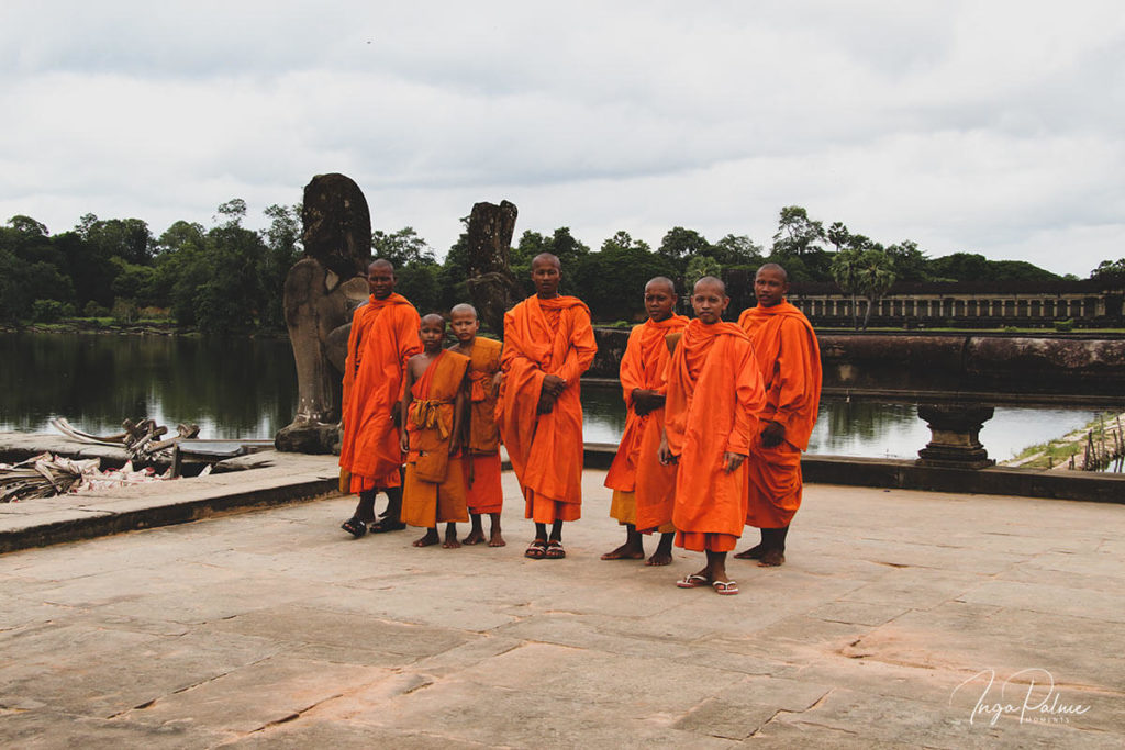 Seven monks posing in front of the water ditch of Angkor Wat. 