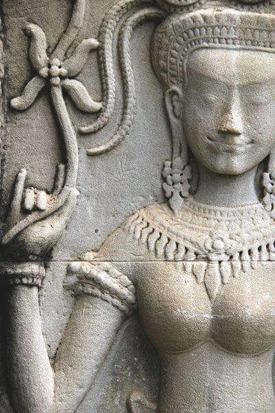Devata holding a flower in her right arm. Carving at Angkor Wat. 