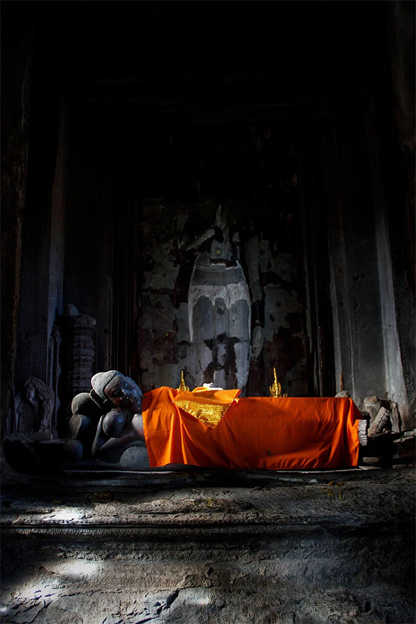 Sleeping Buddha statue in the top tower of Angkor Wat with an organge robe. 